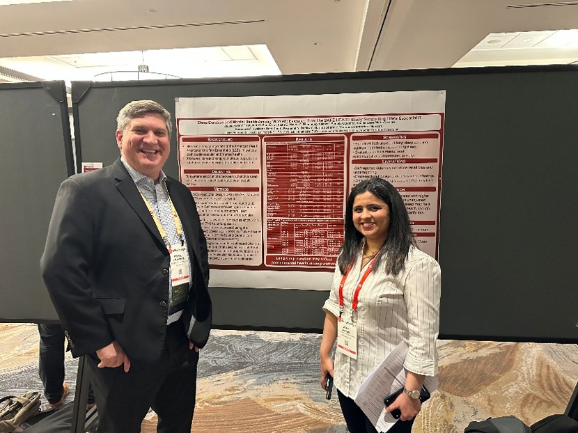 Conference attendees standing beside a research poster